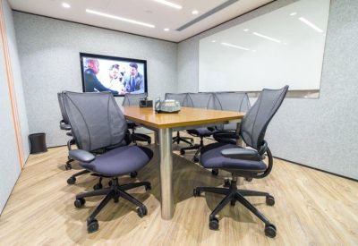 Professional meeting room with a large screen and grey ergonomic chairs.