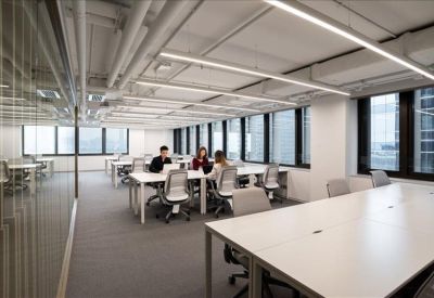 Bright open-plan office with white desks, ergonomic chairs, and large windows.
