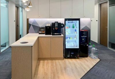 Modern office pantry area with coffee machine and blue booth seating.