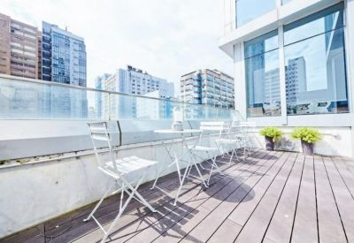 Outdoor wooden terrace with white folding chairs and views of surrounding city buildings.