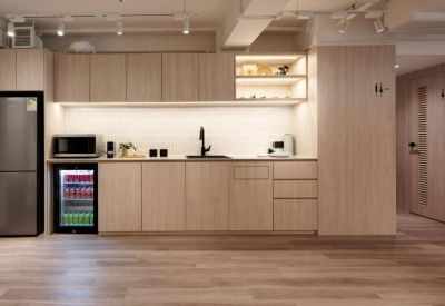 Modern kitchenette with light wood cabinetry and a stocked glass-front beverage fridge.
