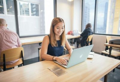 Bright workspace with a person working on a laptop at a light wood desk.