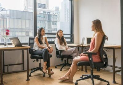 Informal meeting area with three women seated in office chairs near a window.