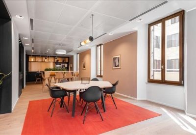 Modern breakout space with a round table and vibrant red rug.
