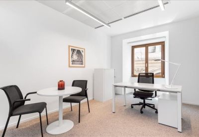 Bright private office suite with white desk and round visitor table.