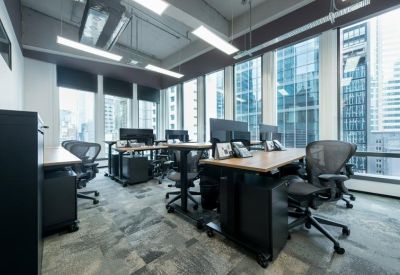 Open-plan workspace featuring height-adjustable desks and ergonomic chairs by large windows.