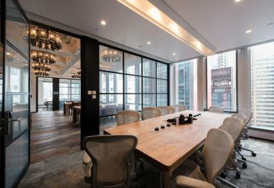 Conference room with a large wooden table, mesh chairs, and glass partition walls.