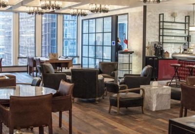 Modern lounge area with leather armchairs and industrial-style ceiling lights.