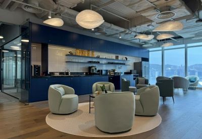 Modern communal kitchen and lounge area with dark blue cabinetry and designer pendant lights.
