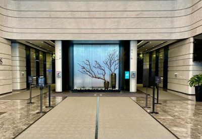 Symmetrical office lobby with a backlit tree art installation and polished marble floors.