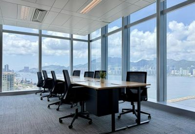 Executive corner office with a large wooden desk and wrap-around windows overlooking the sea.