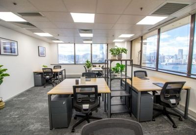 Open-plan office with multiple workstations and large windows overlooking the harbor.