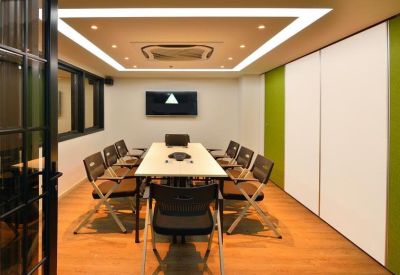 Bright conference room with a long table, ergonomic chairs, and green accent walls.