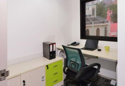Compact office suite with a window, desk, and vibrant green filing drawers.