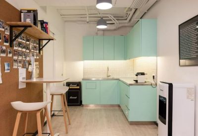 Modern kitchenette with light mint green cabinets and a breakfast bar with high stools.
