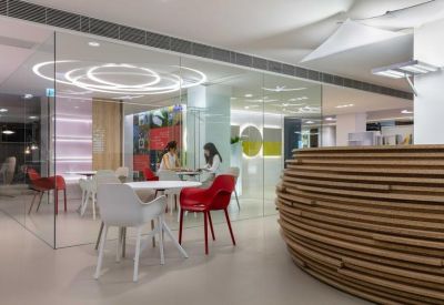 Bright coworking space with a textured wooden reception desk and red chairs.