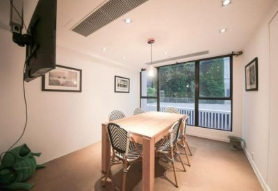 Private meeting room with a wooden table, woven chairs, and wall-mounted television.
