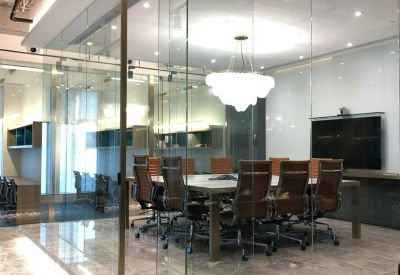 Professional glass-walled meeting room with a large conference table and brown leather chairs.