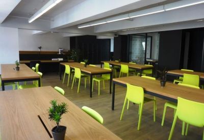 Bright coworking space featuring long wooden tables and vibrant lime green chairs.