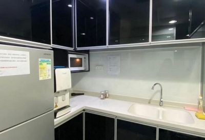 Modern communal kitchen with sleek black cabinetry, white countertops, and integrated appliances.