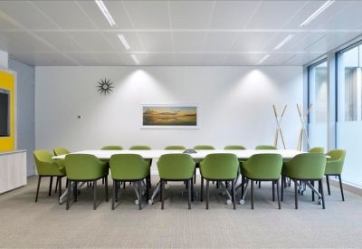 Meeting room with a long white table and bright green chairs.