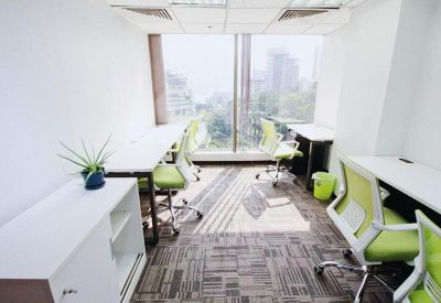 Modern workspace with white desks, lime green chairs, and a large window.
