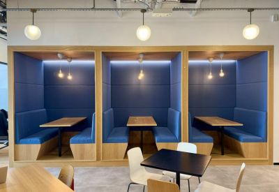 Stylish blue upholstered breakout booths with wooden tables and warm lighting.