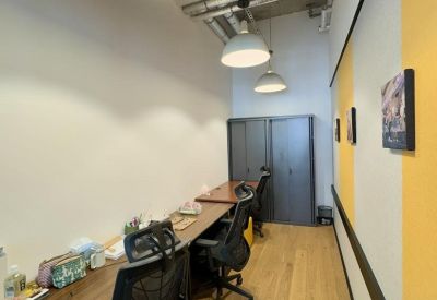 Long wooden workstation with ergonomic chairs and industrial-style pendant lighting.