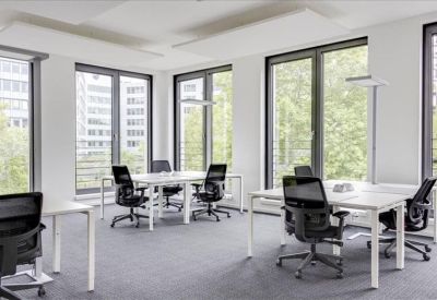 Bright open-plan office area with white desks and black ergonomic chairs.