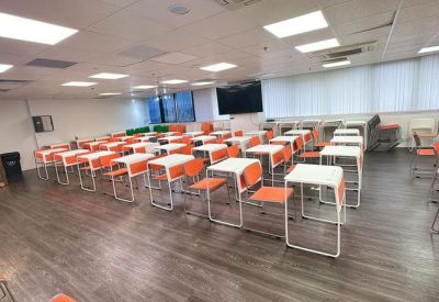 Wide view of a brightly lit training room with tiered seating and a wall-mounted monitor.