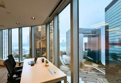 Private office workstation with a wooden desk and floor-to-ceiling windows overlooking the city.