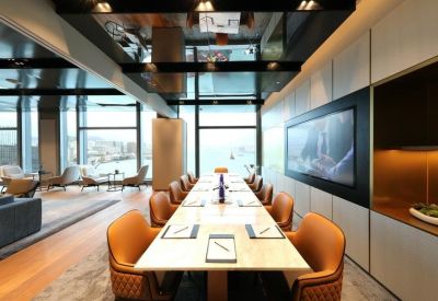 Boardroom with a long marble table, tan leather chairs, and a large wall-mounted screen.