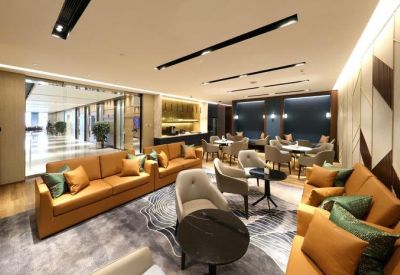 Large breakout space with tan leather sofas, grey armchairs, and colorful pillows.