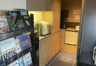 Communal pantry area with wooden cabinetry, coffee machine, and magazine rack.
