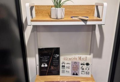 Close-up of a wooden wall-mounted desk with a laptop and a small potted plant.