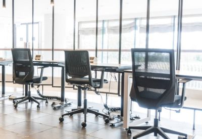 Modern hot-desking area with black mesh chairs and floor-to-ceiling glass partitions.