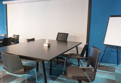 Meeting room with a large projector screen, black table, and blue patterned carpet.