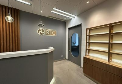 Professional reception area with a dark grey branded wall and elegant wood-toned shelving.