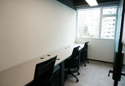 Private four-person office suite with a white desk and large window providing natural light.