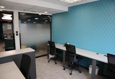 Long workstation area with black ergonomic chairs and a blue patterned feature wall.