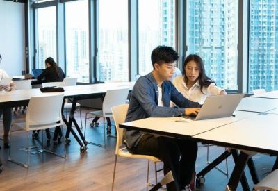 People working in a bright, open-plan workspace at Dah Sing Financial Centre with floor-to-ceiling city views.