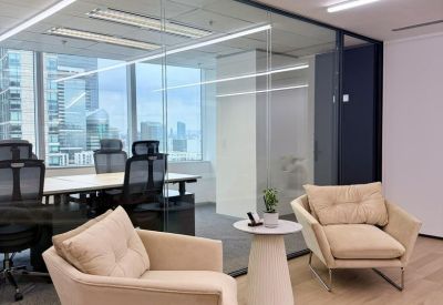 Lounge area with cream armchairs and a small side table overlooking a meeting room.