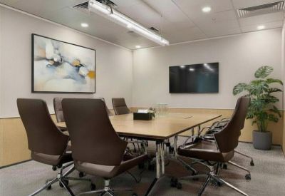 Professional meeting room with a wooden table, brown leather chairs, and wall-mounted screen.