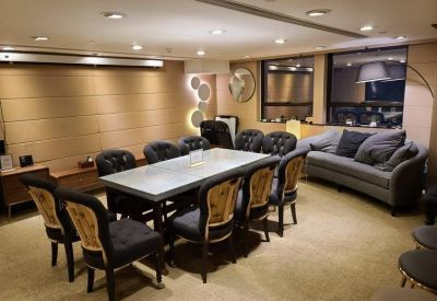 Spacious boardroom with a long table, tufted black chairs, and a grey sofa.