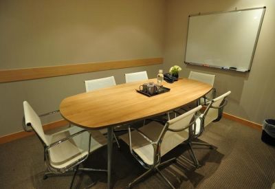 Small private conference room featuring a wooden oval table, white chairs, and a whiteboard.