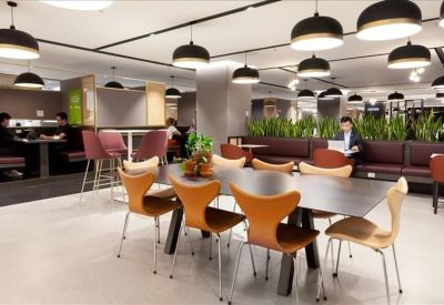 Communal dining area with stylish orange chairs, hanging pendant lights, and indoor plants.