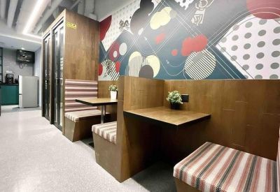 Breakout area with wooden booths, striped seating, and a colorful geometric mural.
