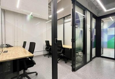Workspace showing a private glass office next to a bright corridor.