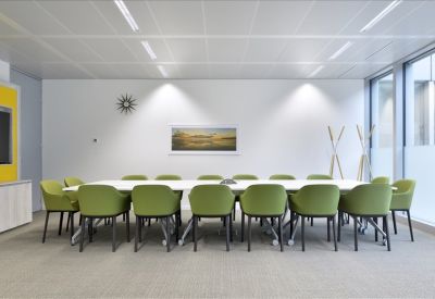 Modern conference room with vibrant green chairs and sleek white table.