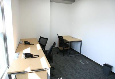 Compact private office with two desks and black chairs.